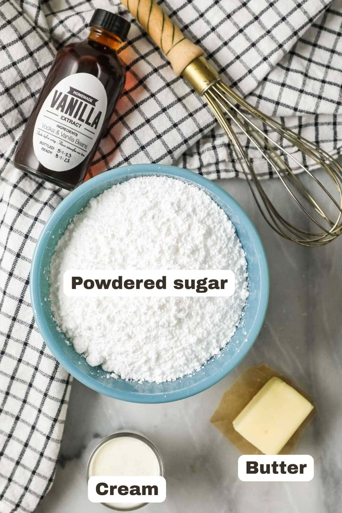 Overhead view of labeled ingredients including powdered sugar, vanilla, butter, and cream.