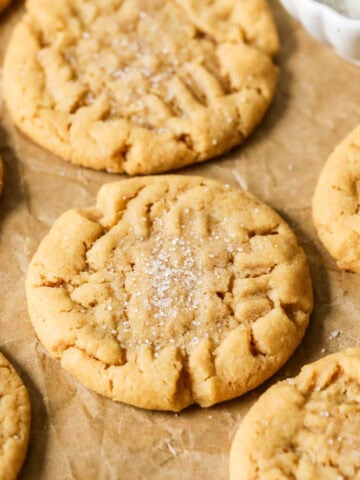 Sourdough peanut butter cookies with sugared tops on brown parchment paper.
