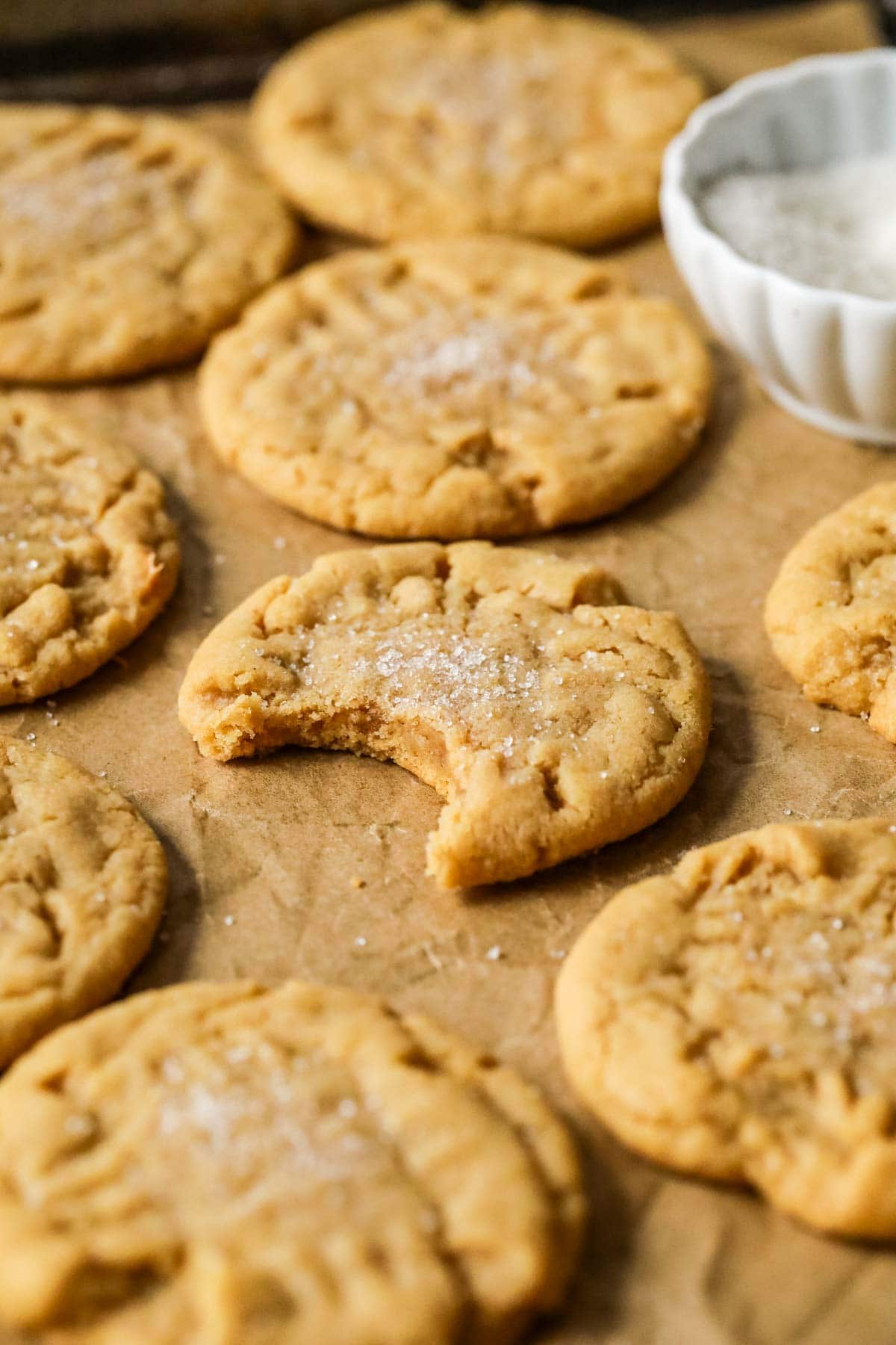 Baking tray of sourdough peanut butter cookies with the center cookie missing a bite.
