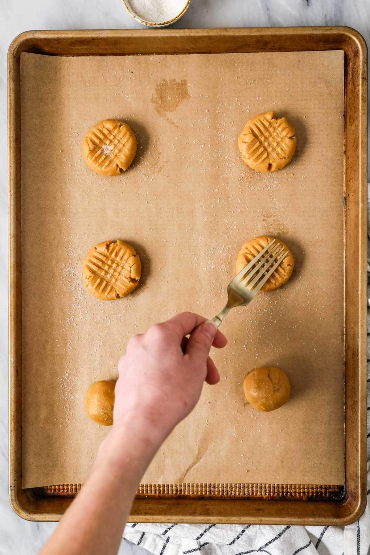 Fork flattening sourdough peanut butter cookies before baking.