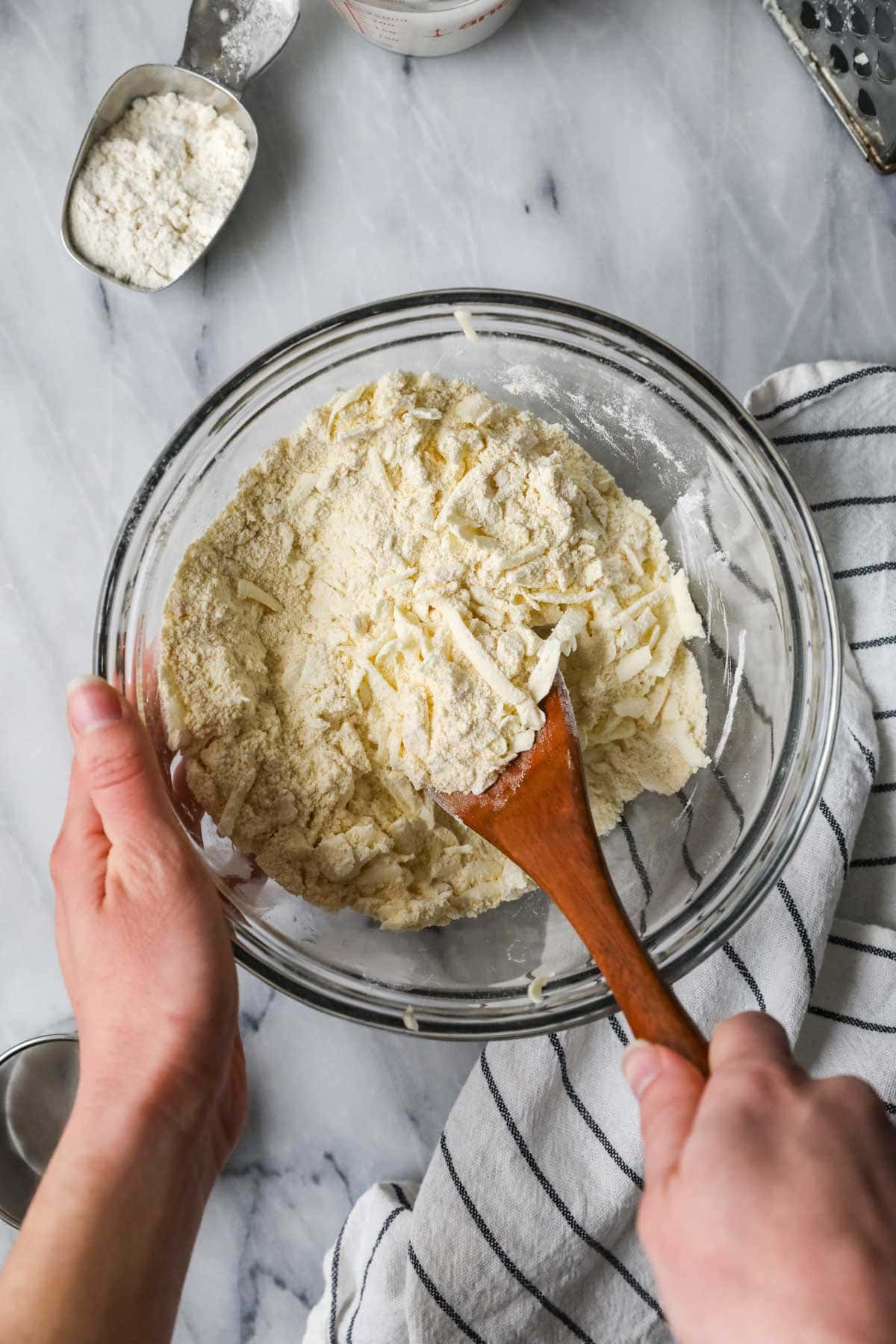 Overhead view of butter shreds being stirred into a cornmeal mixture.