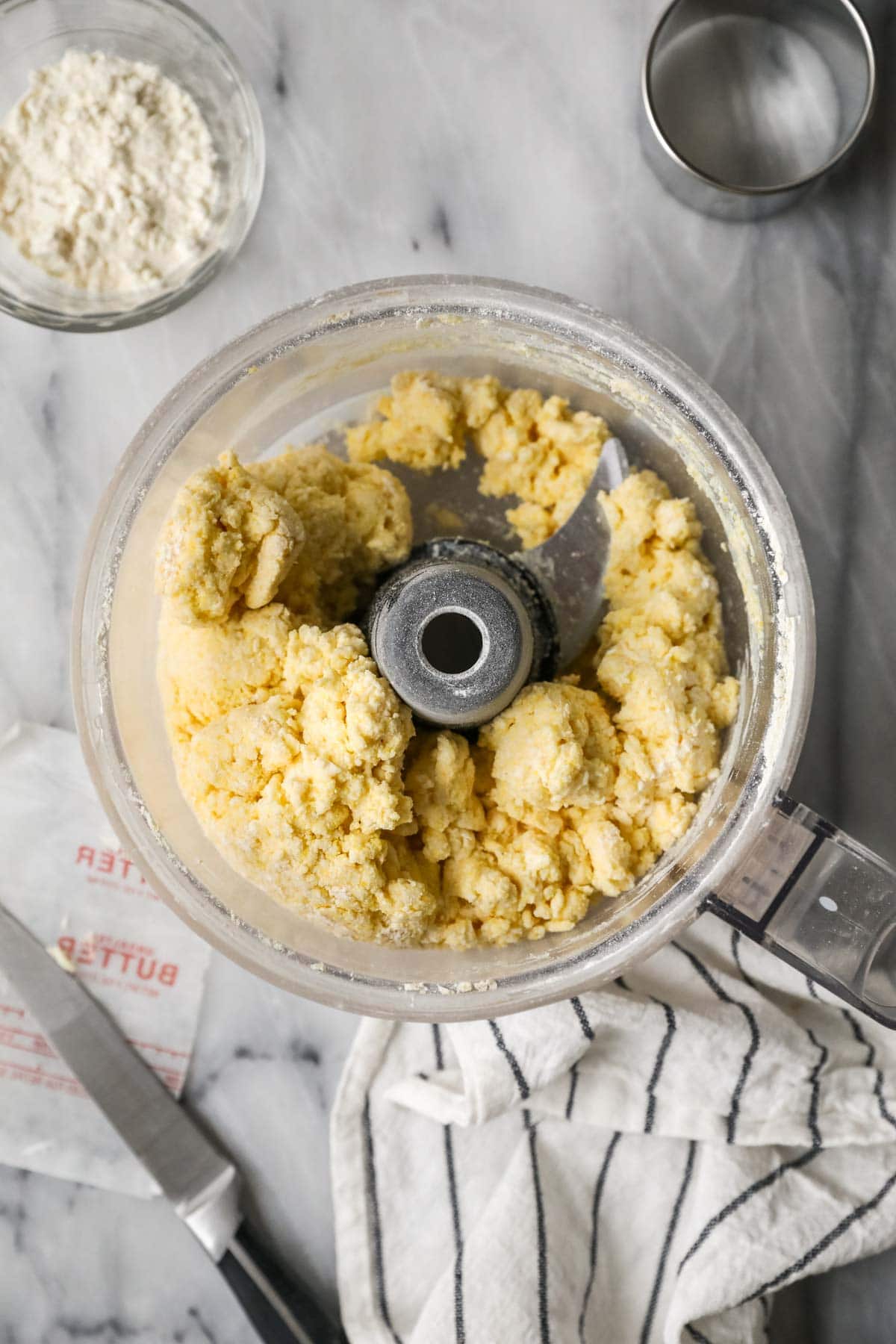 Overhead view of a cornbread biscuit dough being prepared in a food processor.