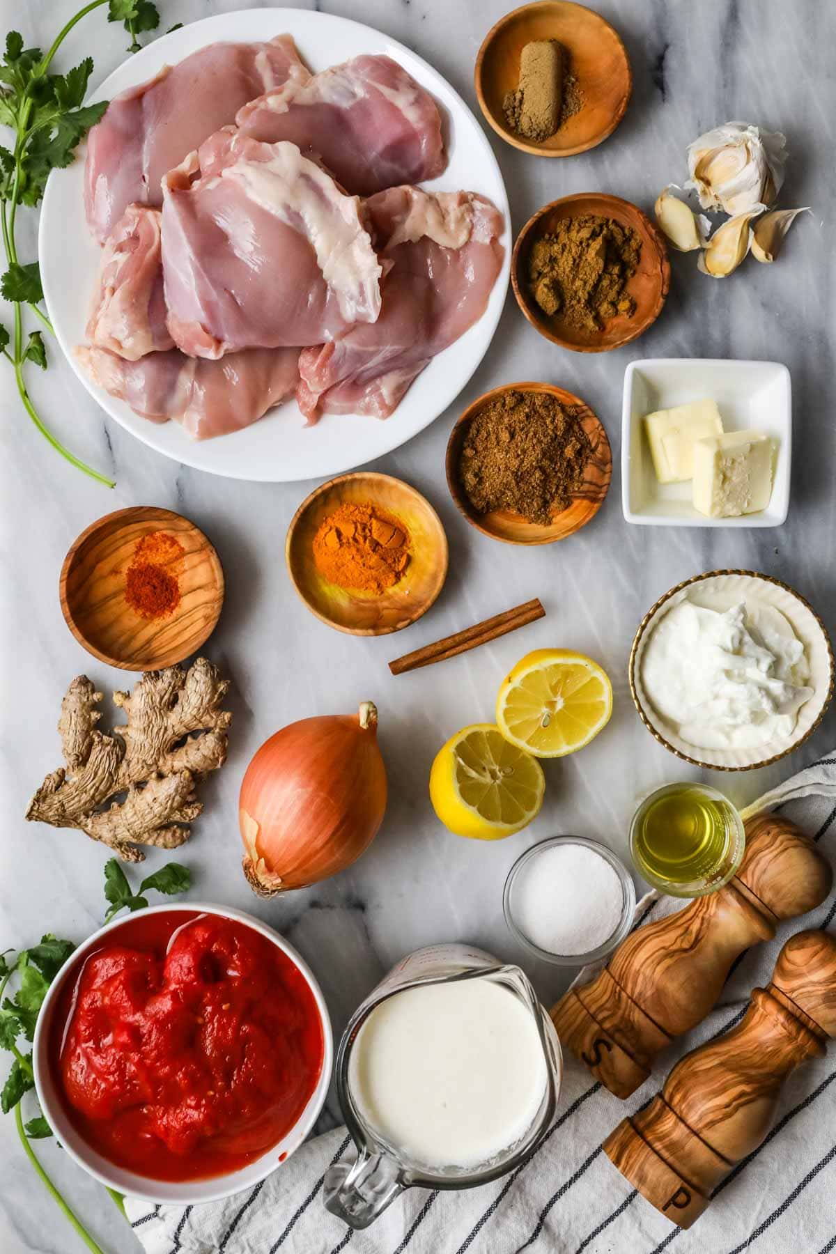Overhead view of ingredients including chicken thighs, fresh ginger, garam masala, and more.