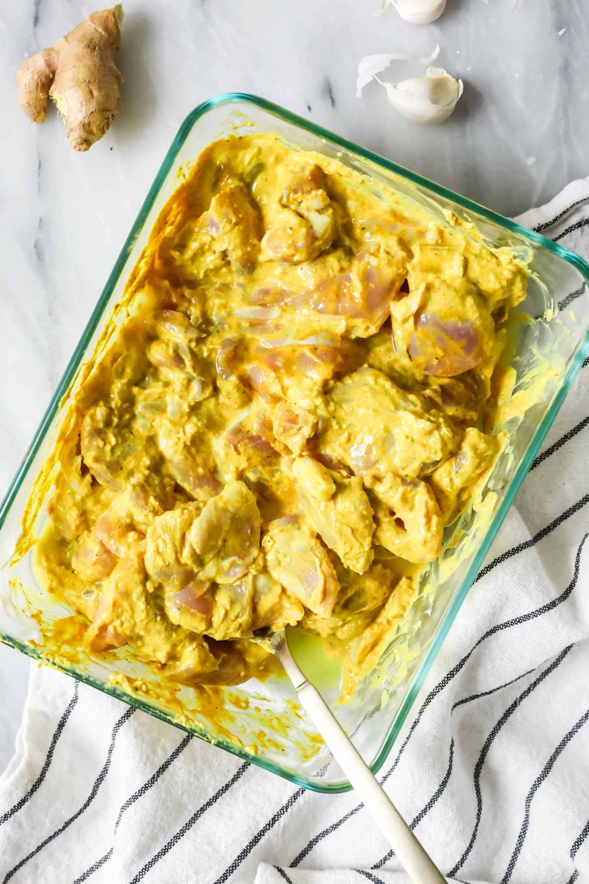 Overhead view of chicken thighs marinating in a yogurt sauce.