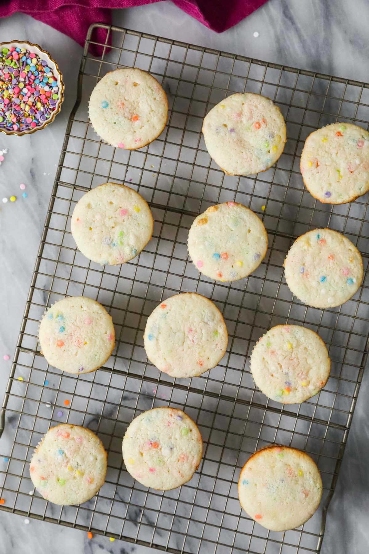 Overhead view of unfrosted confetti cupcakes on a cooling rack.