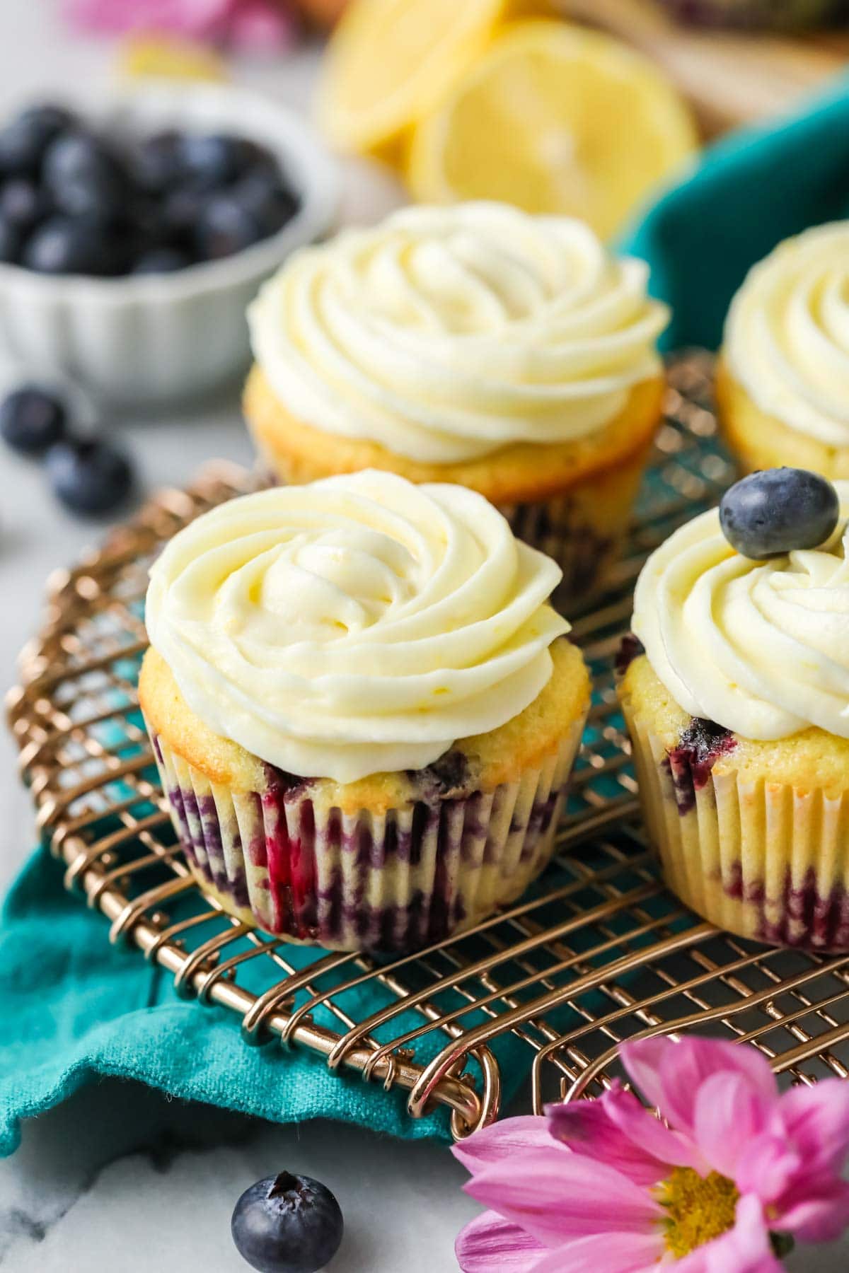Blueberry lemon cupcakes topped with icing swirls on a cooling rack.