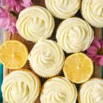 Overhead view of cupcakes frosted with lemon cream cheese frosting among lemon halves.