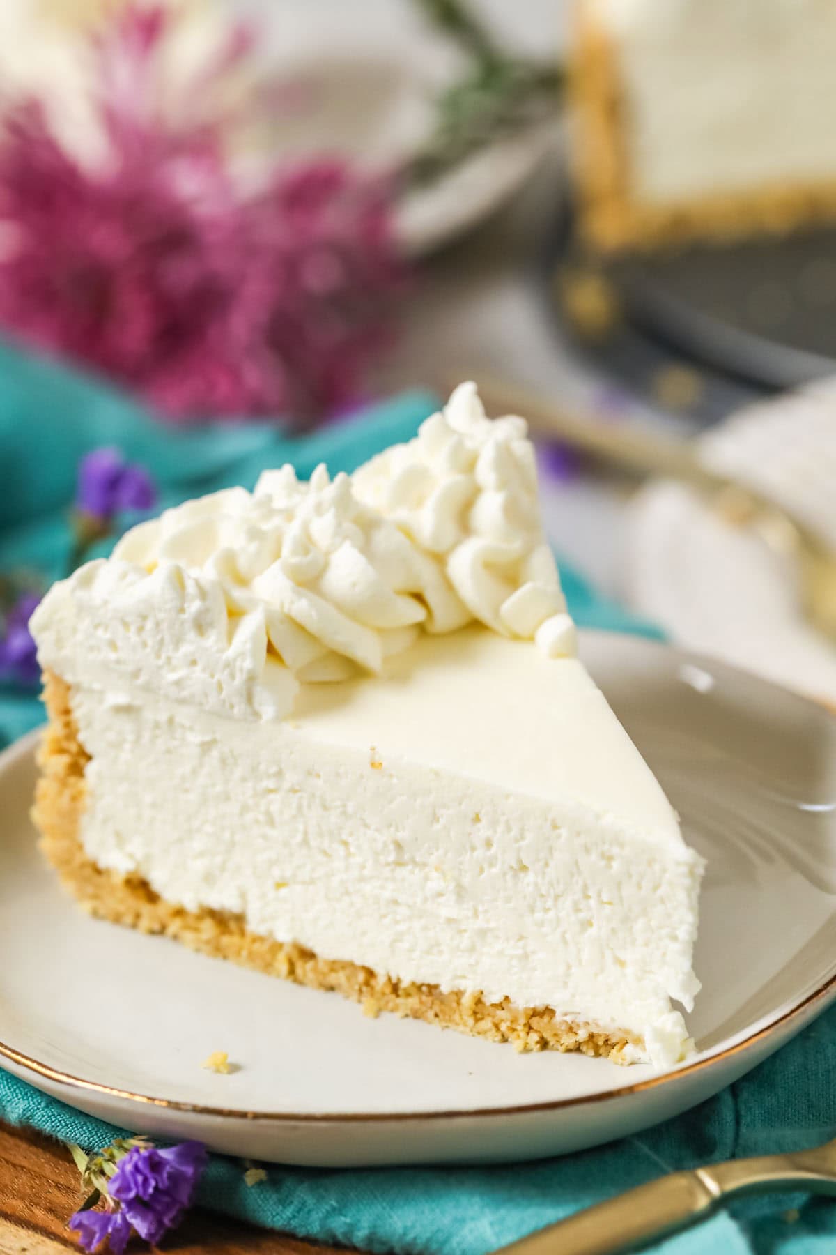 Slice of no-bake cheesecake with a whipped cream topping on a plate.