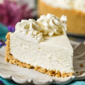 Slice of no-bake cheesecake with a whipped cream topping on a plate.