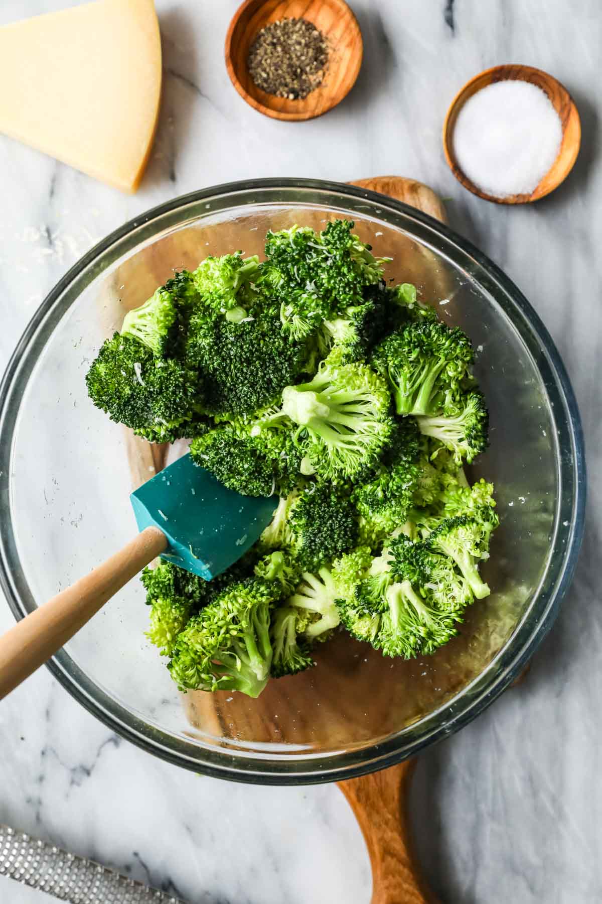Overhead view of a bowl of broccoli that's been tossed with oil and seasonings.