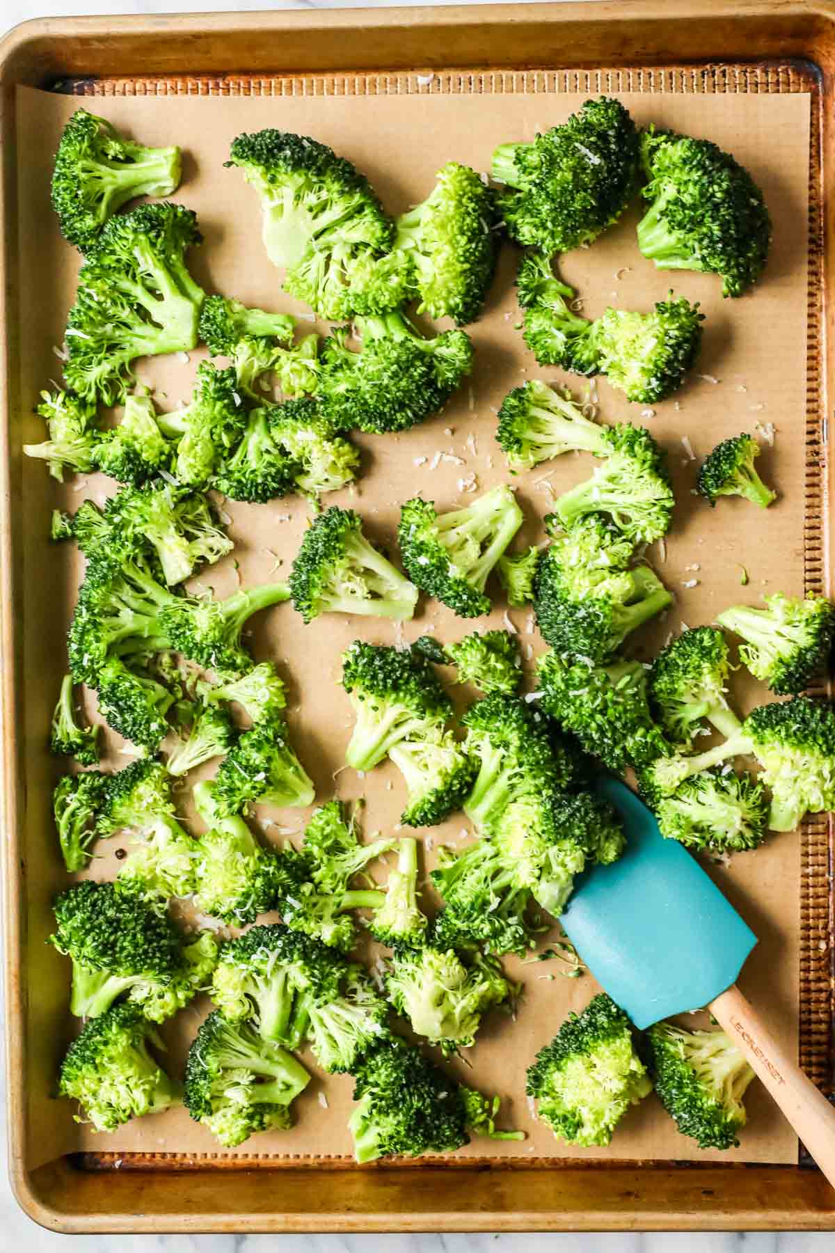 Overhead view of a sheet pan of broccoli before roasting in the oven.