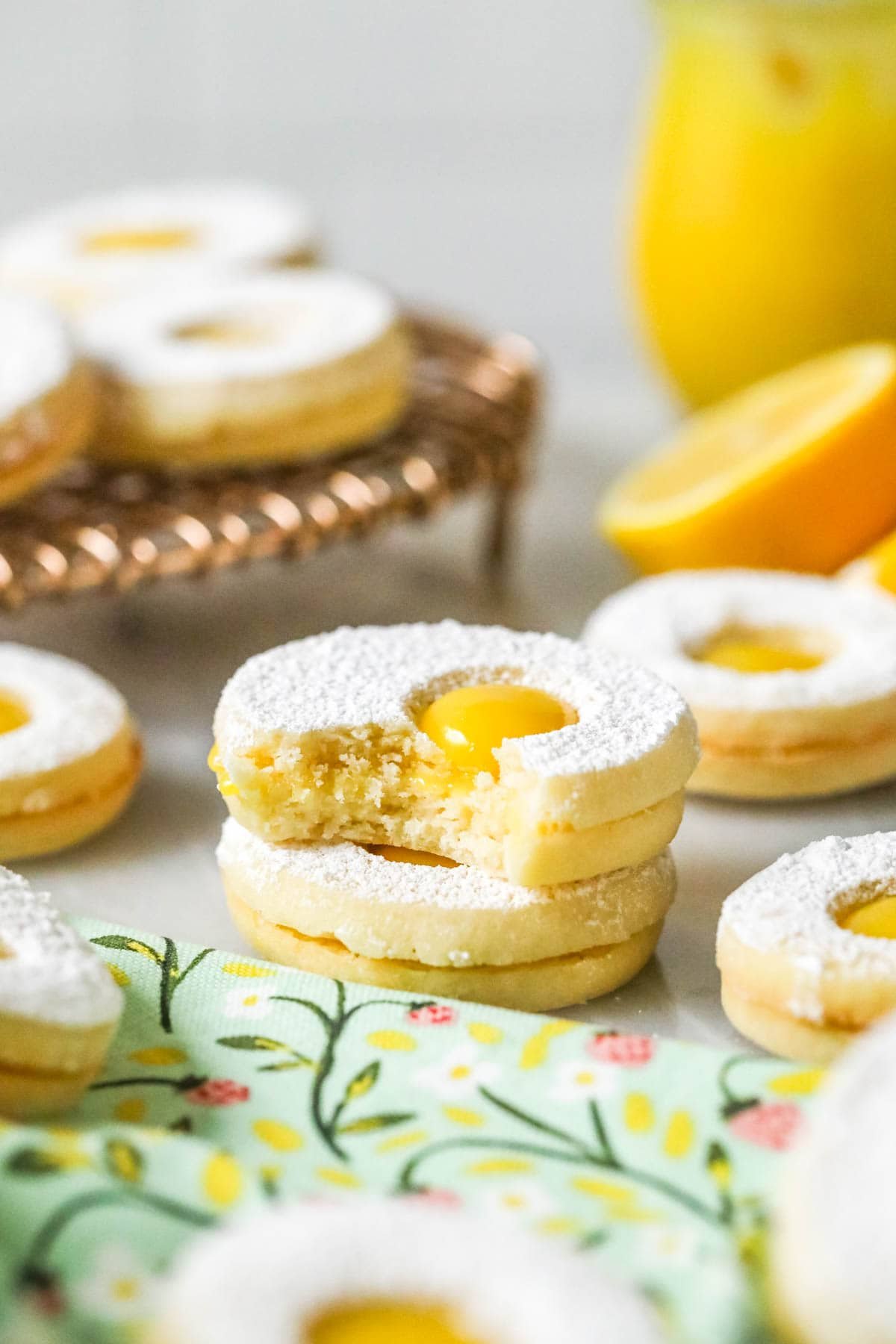 Stack of lemon curd filled cookies with the top cookie missing a bite.