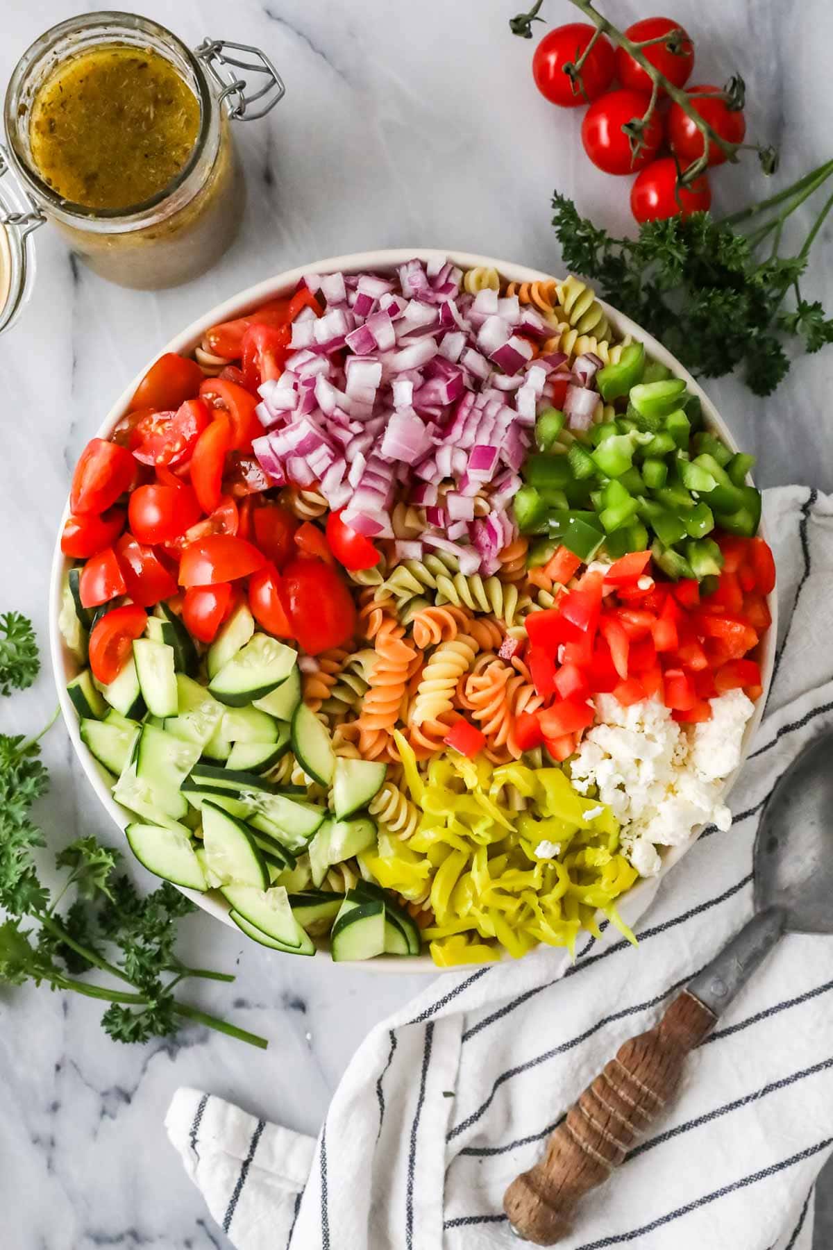 Overhead view of vegetables and pasta in a bowl before mixing.