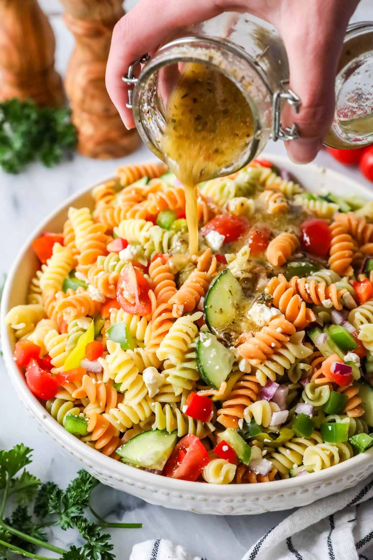 Dressing being poured over pasta salad.