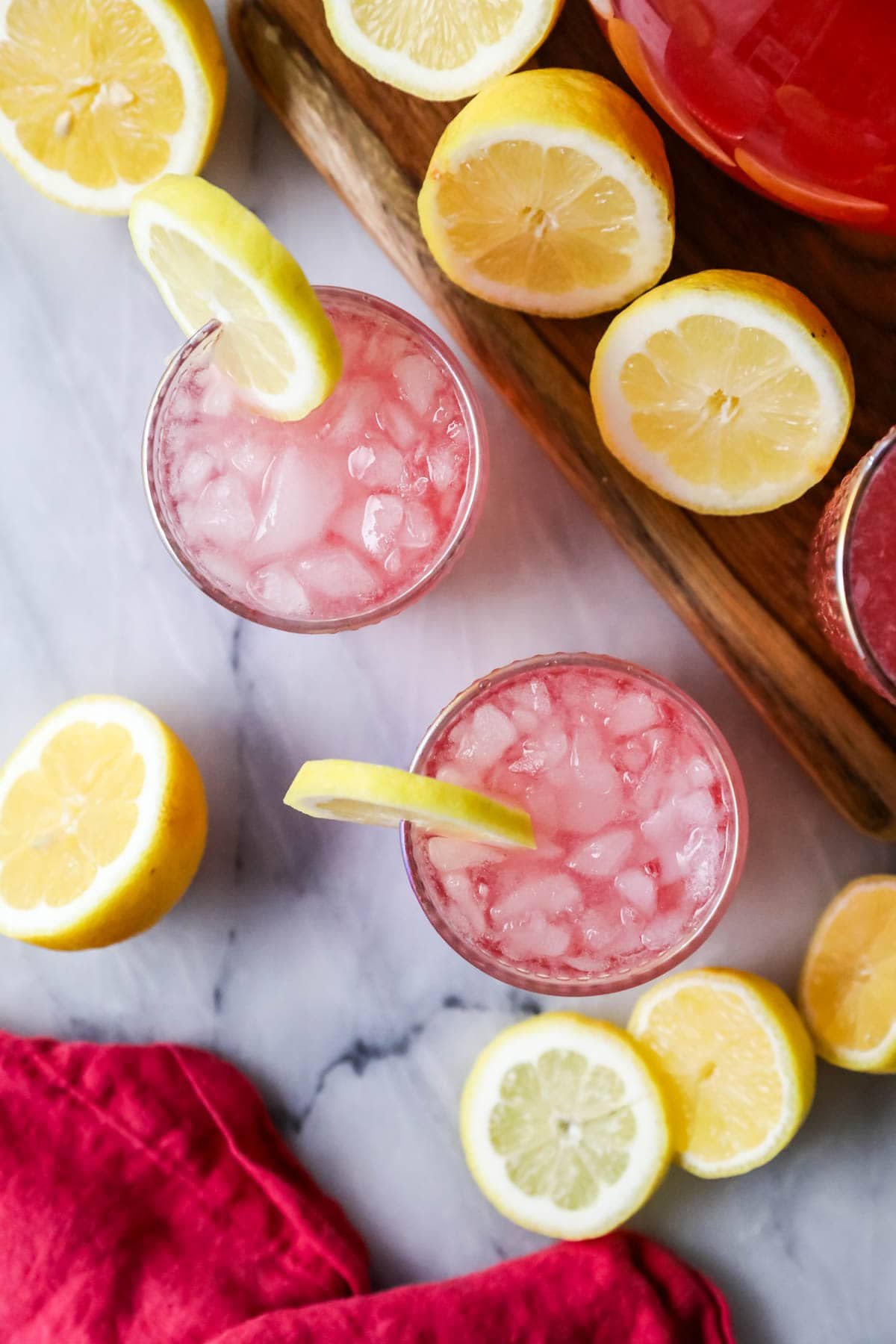 Overhead view of glasses of pink lemonade garnished with lemon slices.