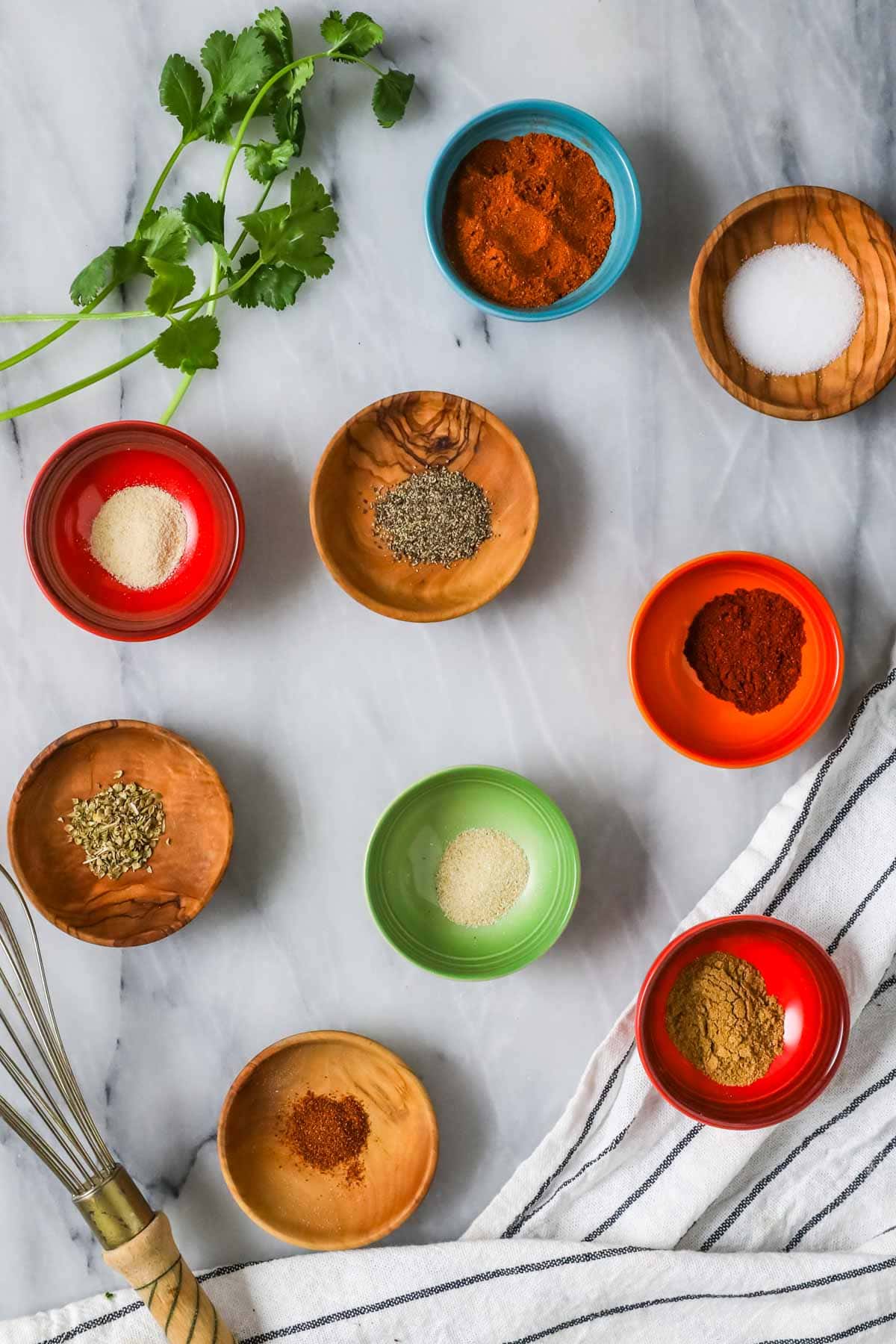 Overhead view of nine small colorful dishes of spices.