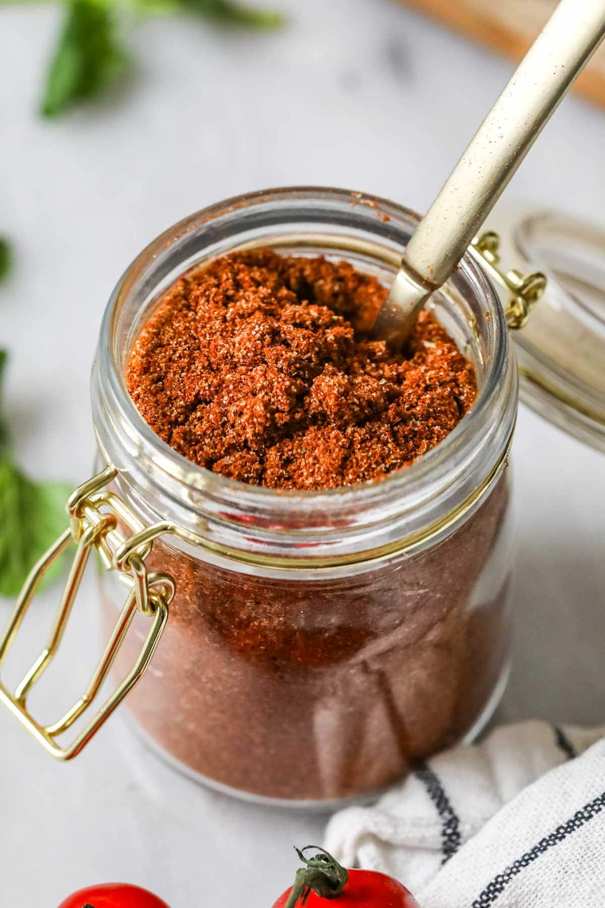 Jar of homemade taco seasoning with a gold spoon inside.