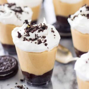 Peanut butter pie dessert shooters topped with whipped cream and Oreo crumbs.