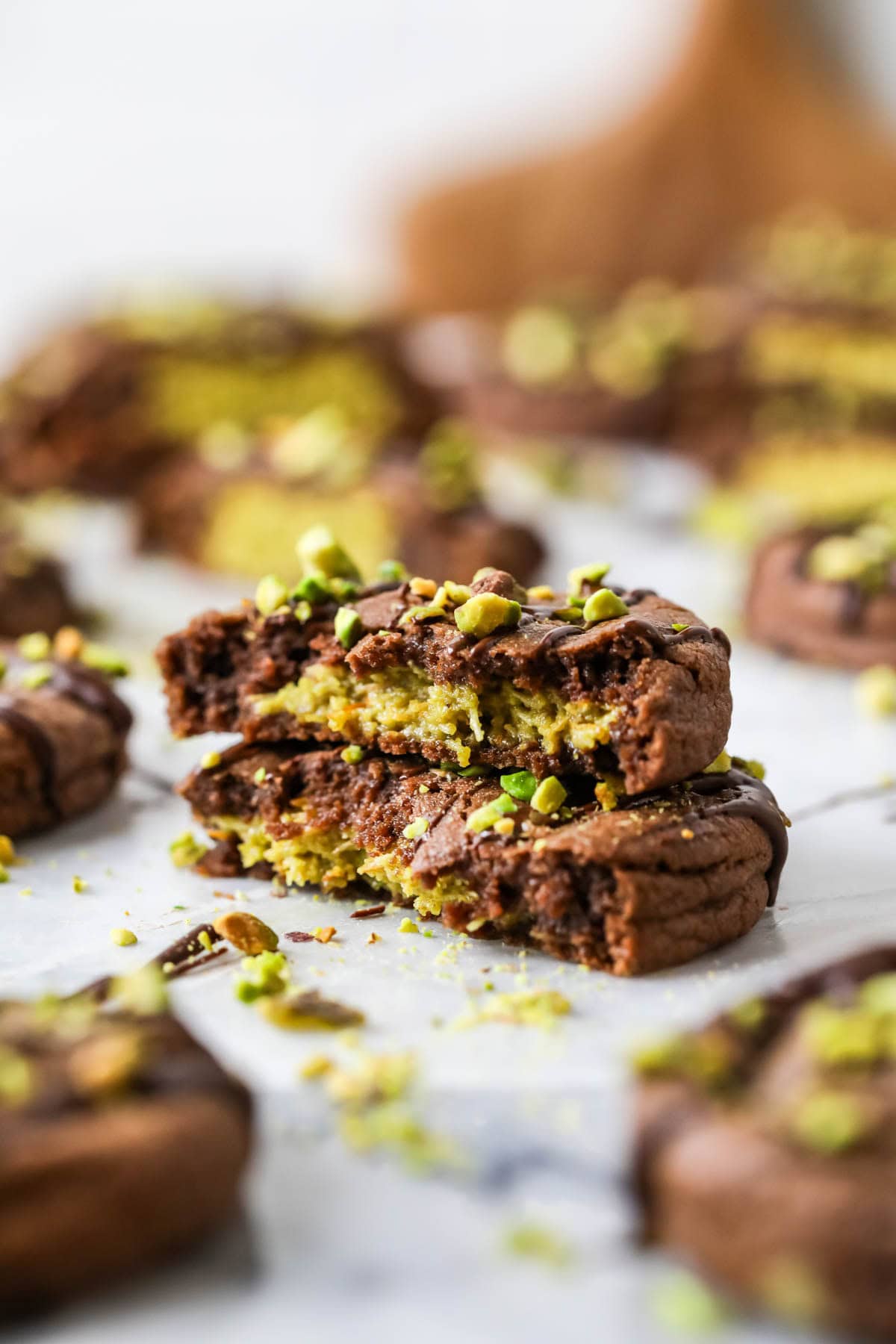 Two stacked halves of a Dubai chocolate cookie filled with pistachio cream and kataifi. 
