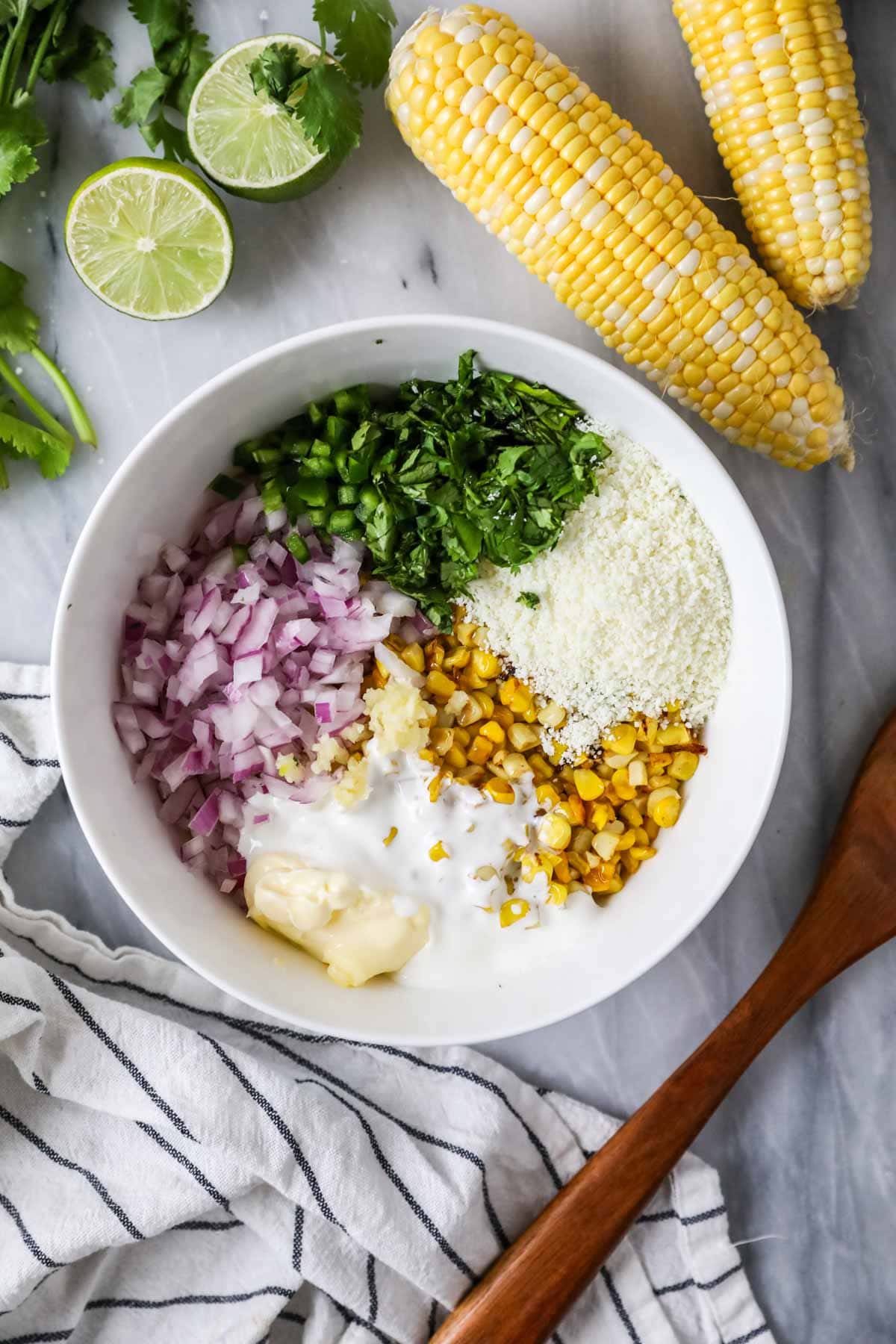 Overhead view of a bowl of ingredients including charred corn, cotija cheese, cilantro, and more.