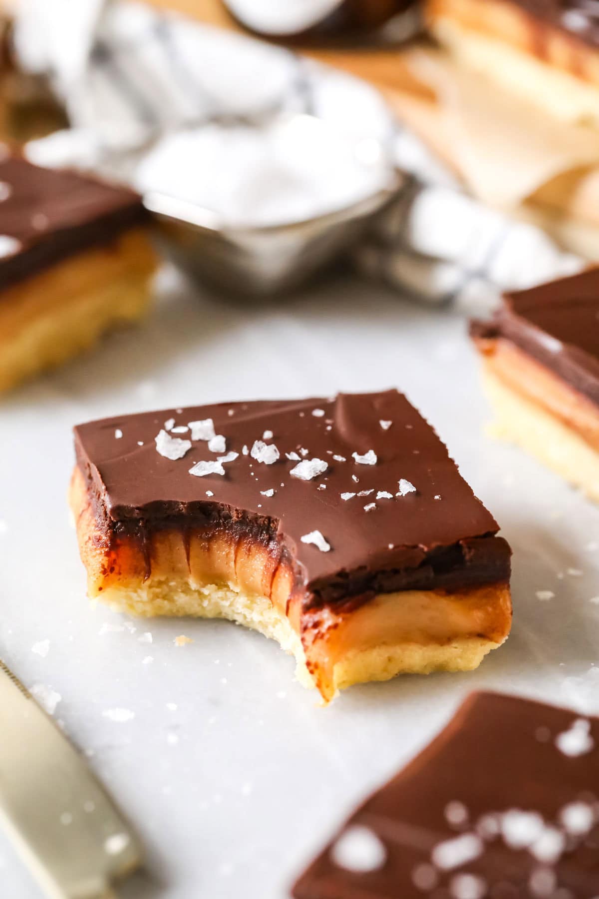 Square of millionaire's shortbread with a bite missing, showcasing thick caramel center. 