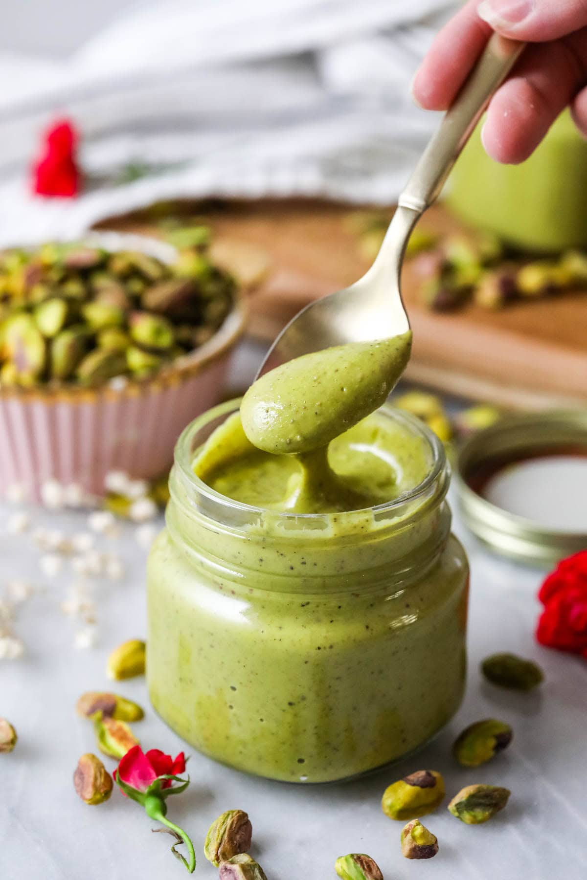 Spoon dipping into a small jar of homemade pistachio cream. 