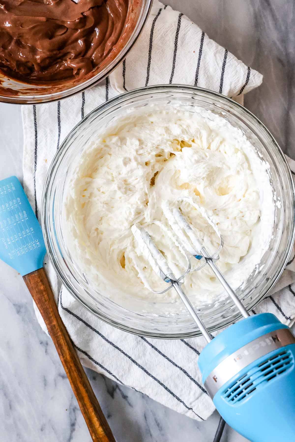 Overhead view of cream being whipped to stiff peaks with an electric mixer.