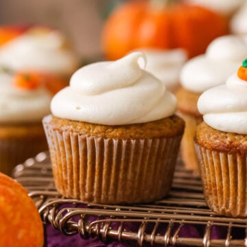 Pumpkin cupcake topped with a brown sugar cream cheese frosting on a cooling rack.