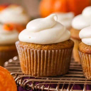 Pumpkin cupcake topped with a brown sugar cream cheese frosting on a cooling rack.