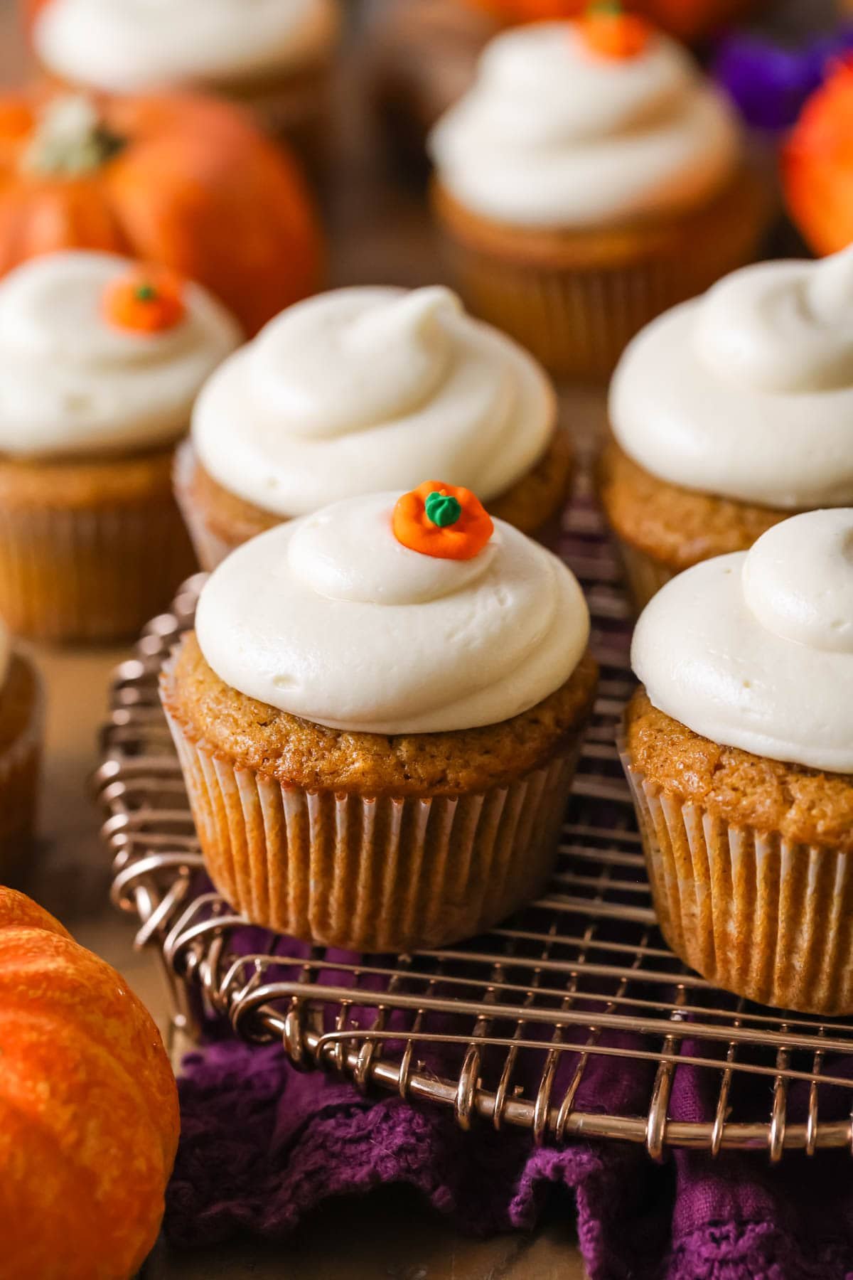 Cupcakes made with pumpkin topped with swirls of cream cheese frosting and a pumpkin candy.
