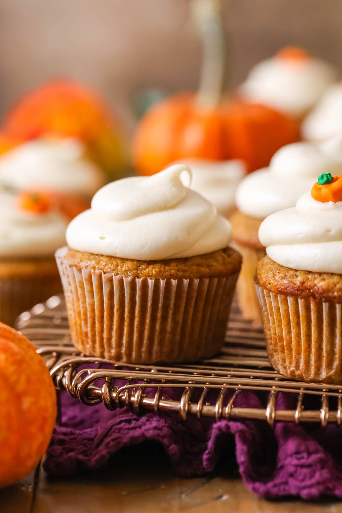 Pumpkin cupcake topped with a brown sugar cream cheese frosting on a cooling rack.