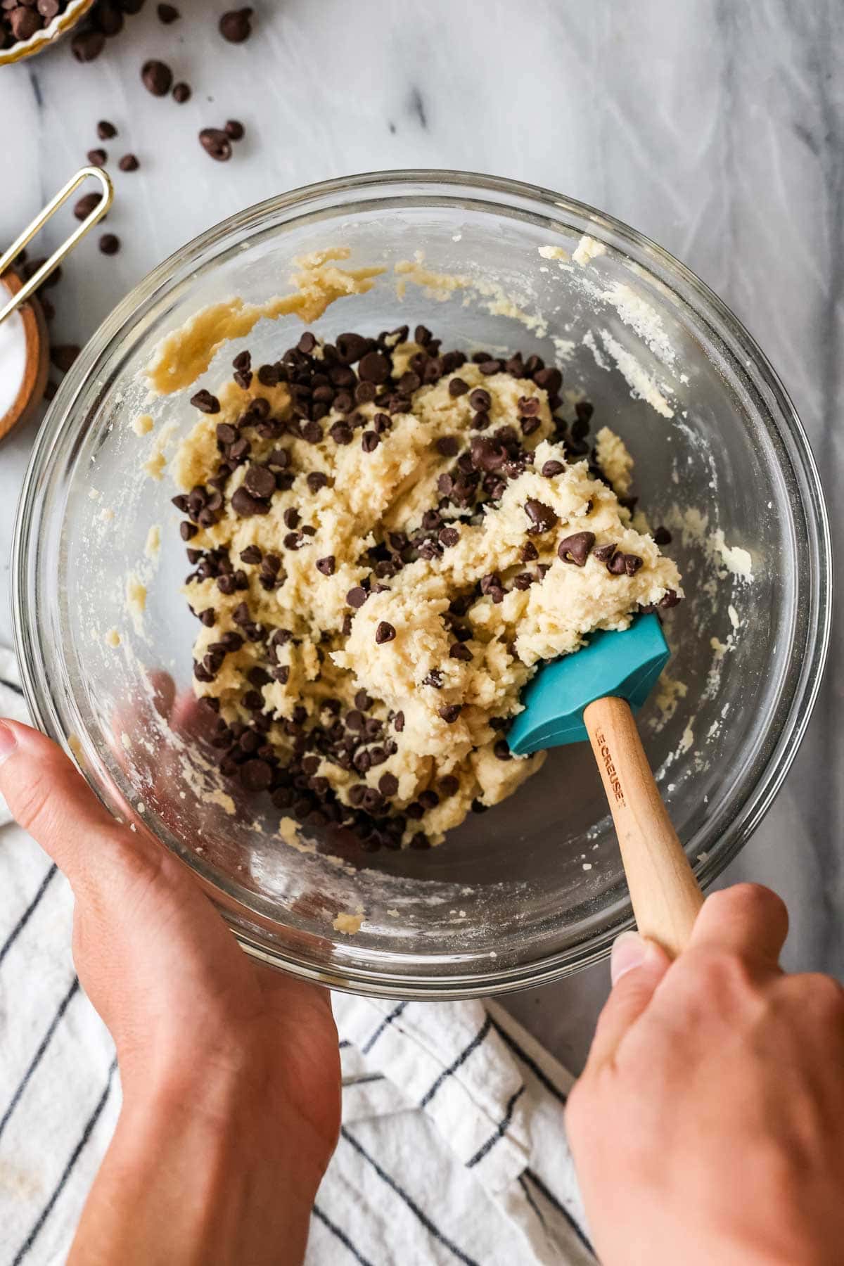 Overhead view of chocolate chips being folded into a cookie brittle batter.