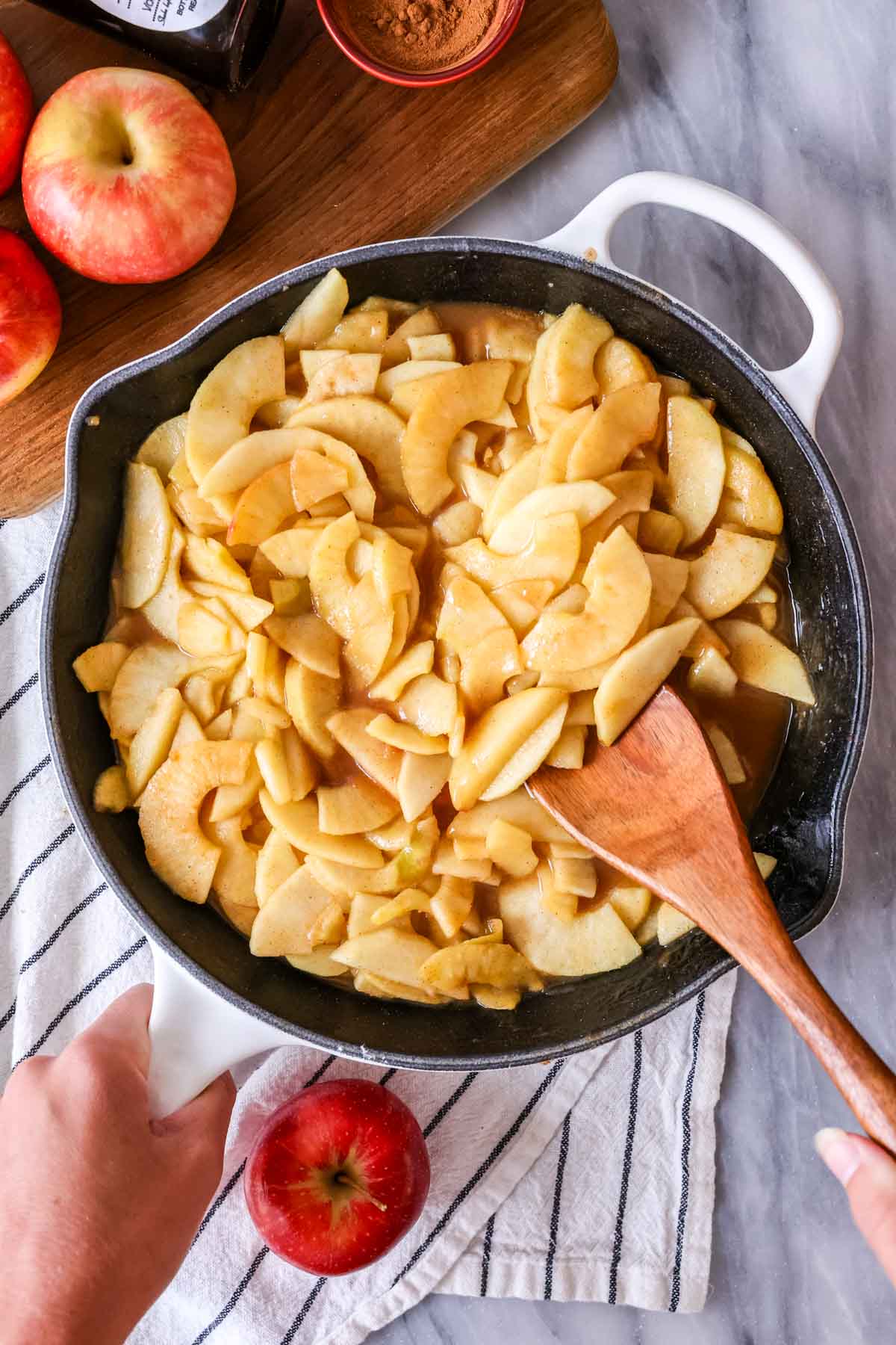 Overhead view of sliced apples cooking in a cast iron pan.