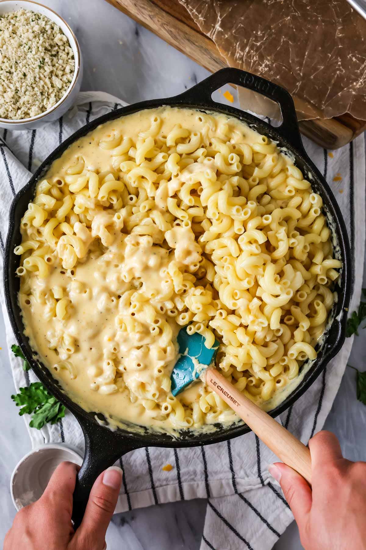 Stirring macaroni noodles into cheese sauce for my baked mac and cheese recipe.