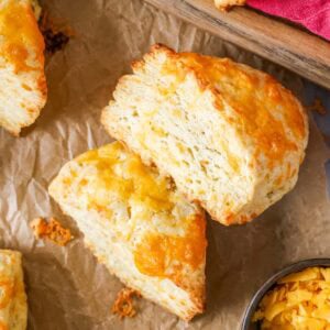 Overhead view of wedge shaped cheese scones with the top scone on its side to show flaky layers.