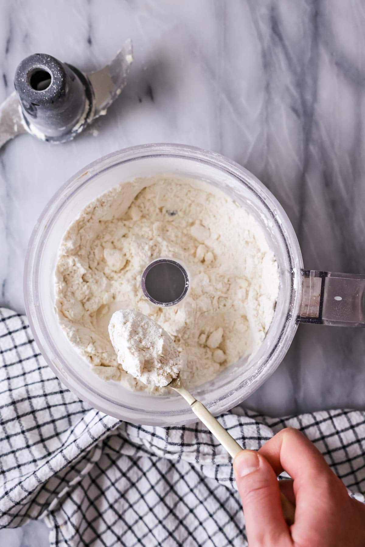Overhead view of butter bits that have been pulsed into dry ingredients in a food processor.