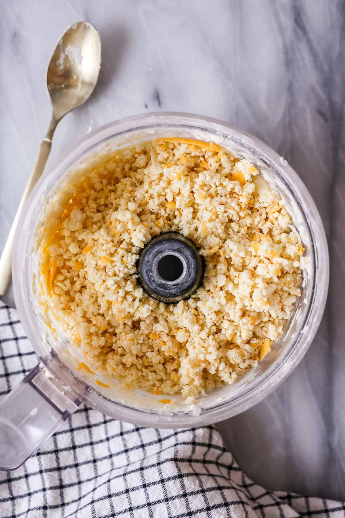 Overhead view of a scone dough after pulsing in cream in the bowl of a food processor.