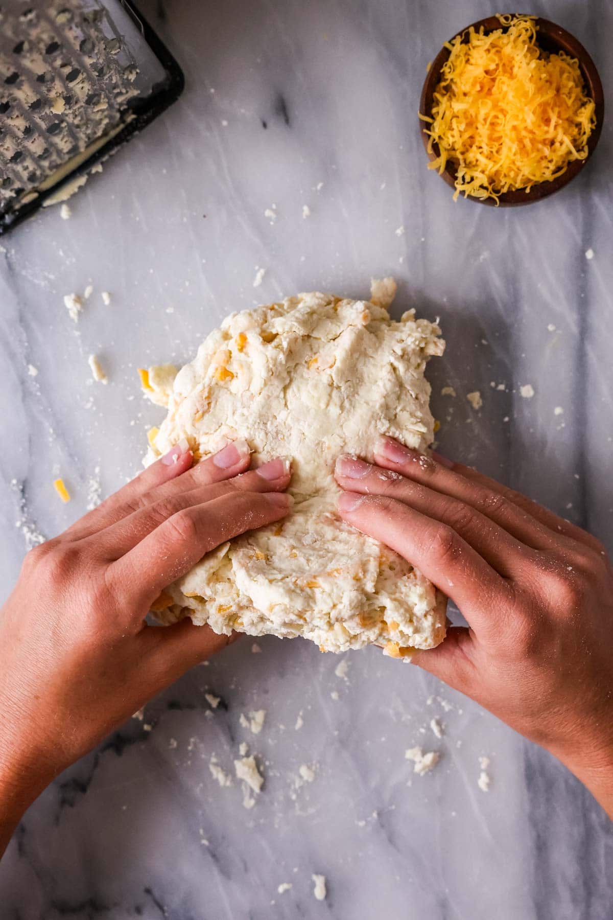 Hands folding a scone dough over itself to create flaky layers.