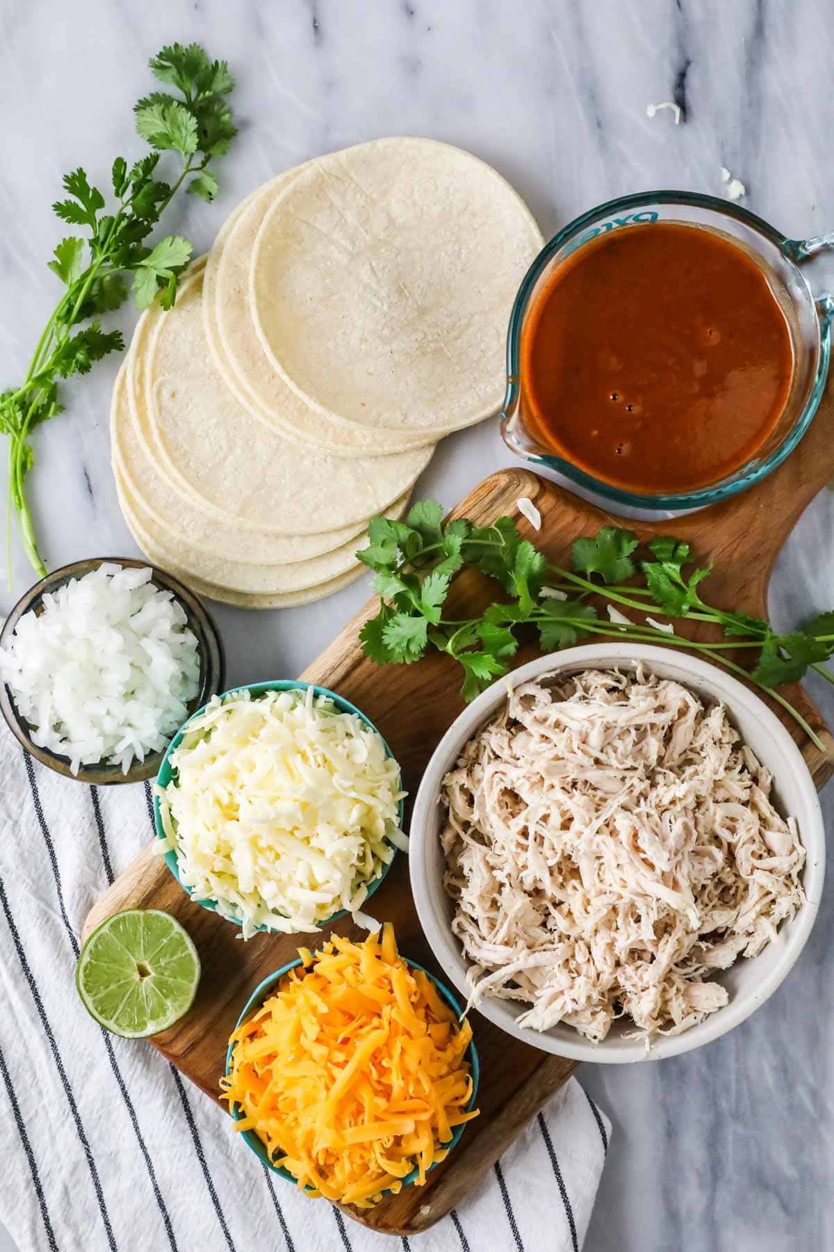 Overhead view of ingredients including tortillas, shredded chicken, cheese, and more.