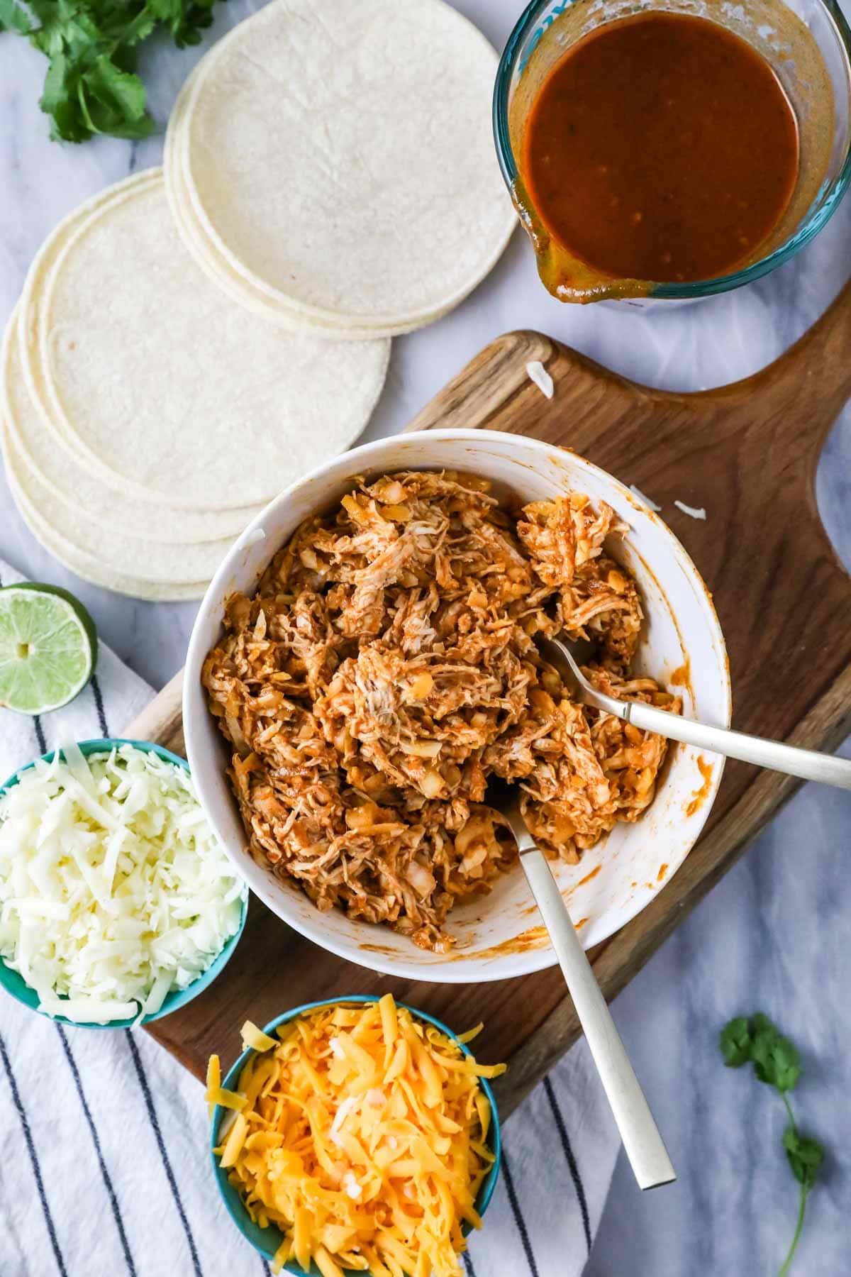 Overhead view of a bowl containing shredded chicken, cheese, onions, and enchilada sauce all mixed together.