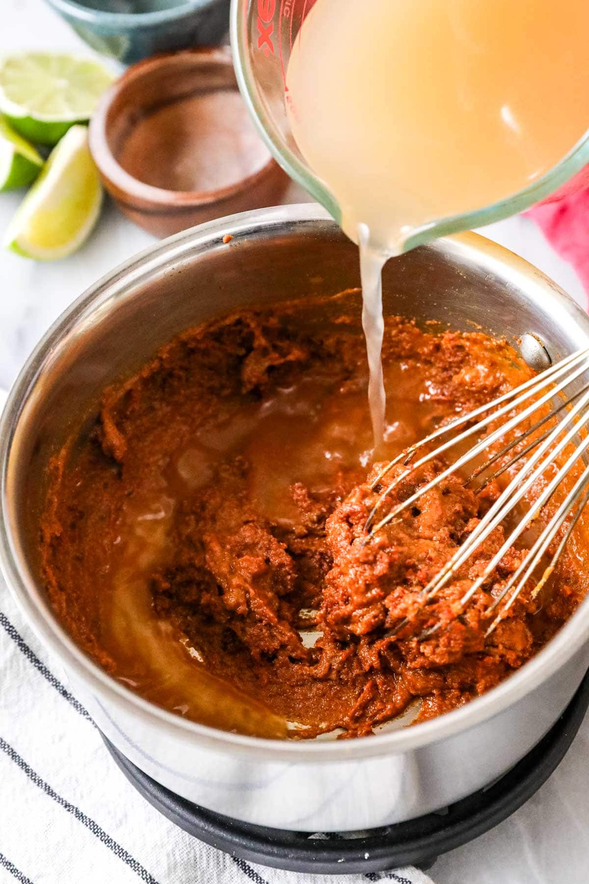 Pouring chicken broth into a spiced roux to make a sauce for enchiladas.