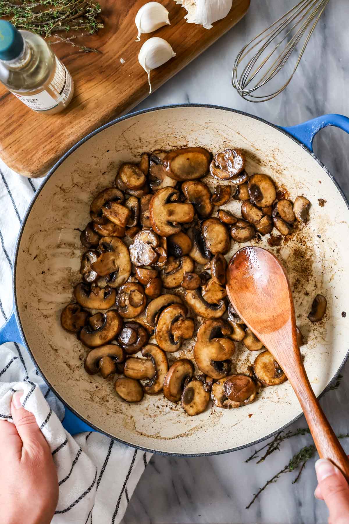 Overhead view of mushrooms sautรฉing in a skillet.