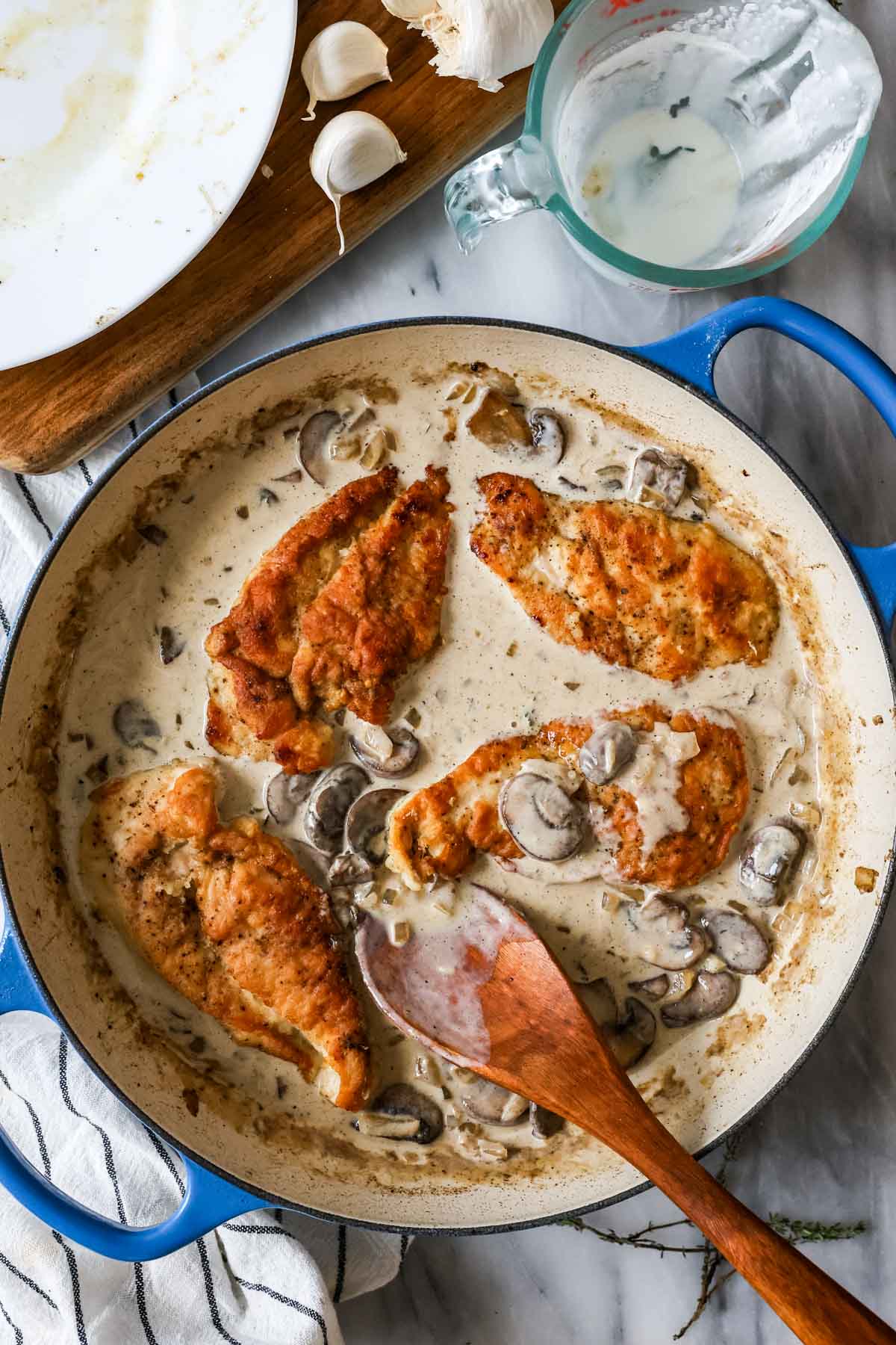 Overhead view of chicken cutlets in a skillet with a creamy mushroom sauce.