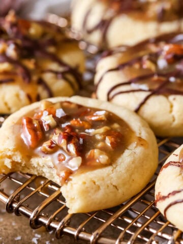 Pecan pie cookies on a cooling rack with the front cookie missing a bite.