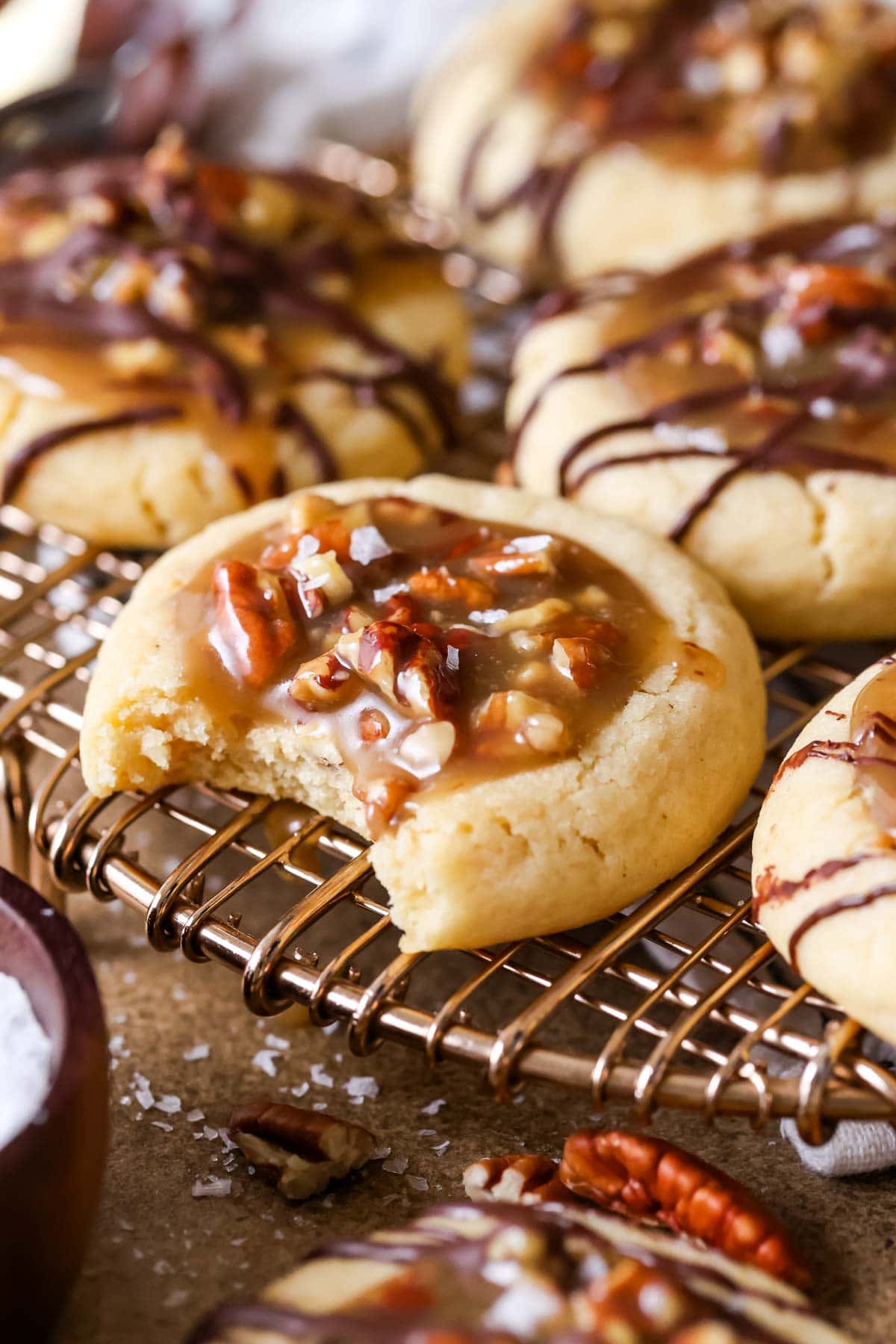 Pecan pie cookies on a cooling rack with the front cookie missing a bite.