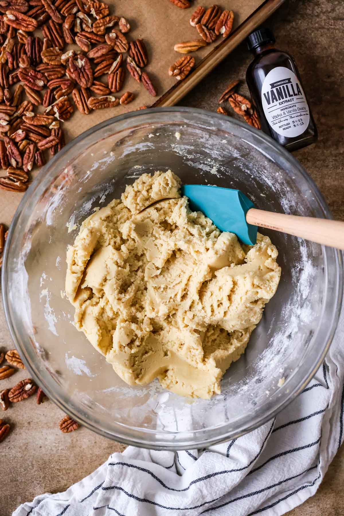 Overhead view of a bowl of cookie dough with a blue spatula in it.