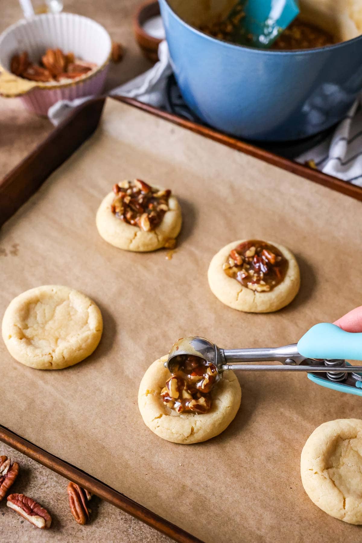 Scooping pecan pie filling into shortbread cookie shells.