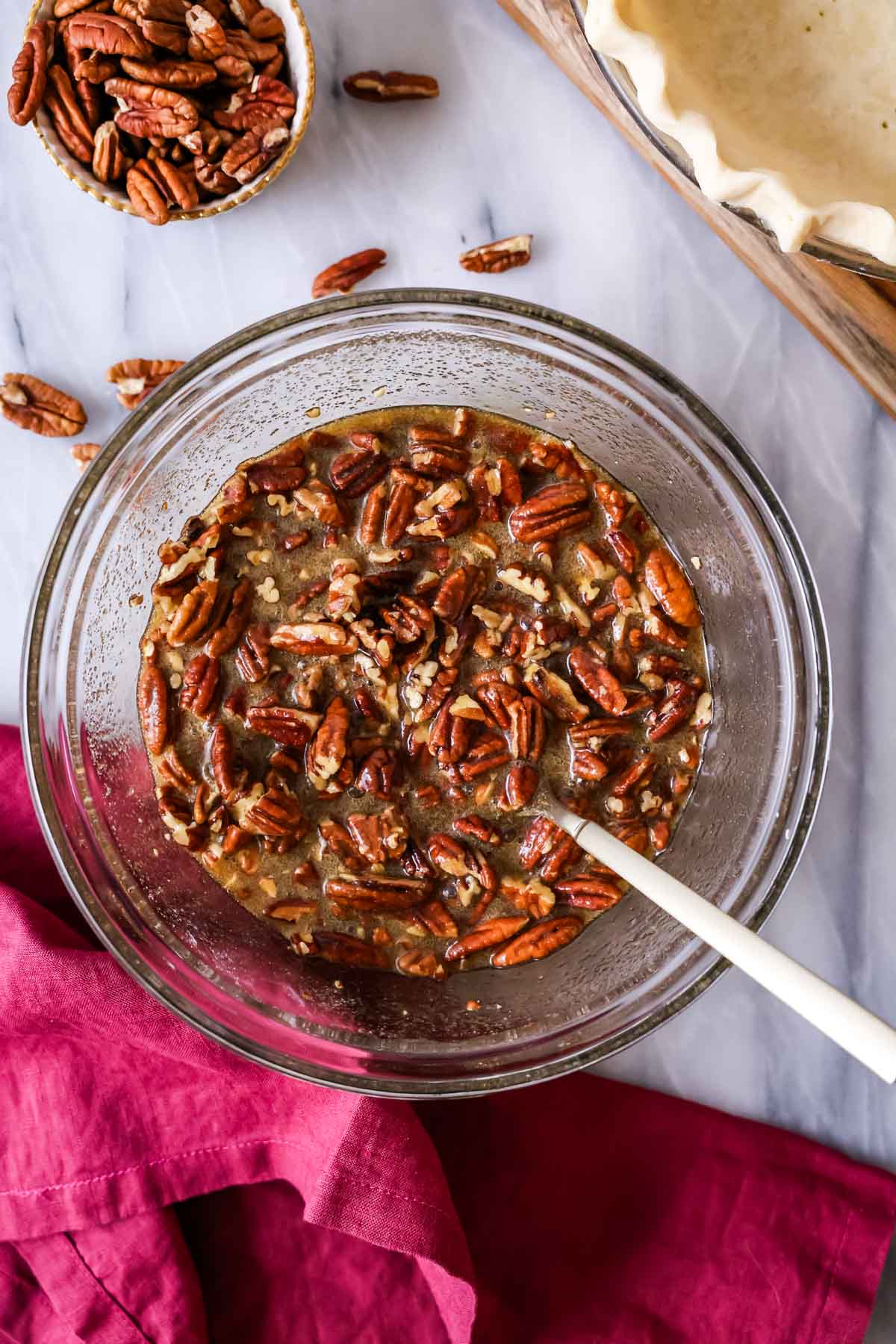 Overhead view of a bowl of toasted pecans, eggs, and more being stirred together for a pie.