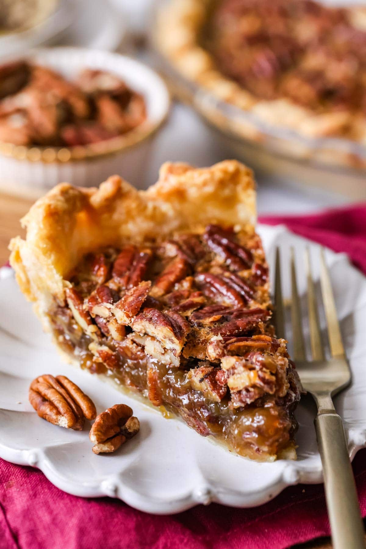 Slice of pecan pie on a plate with a fork beside it.