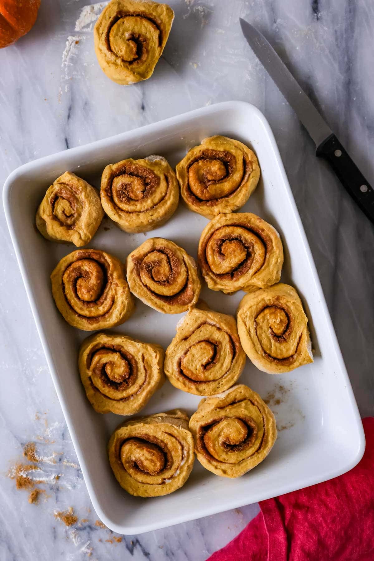 Overhead view of pumpkin cinnamon rolls in a pan before baking.
